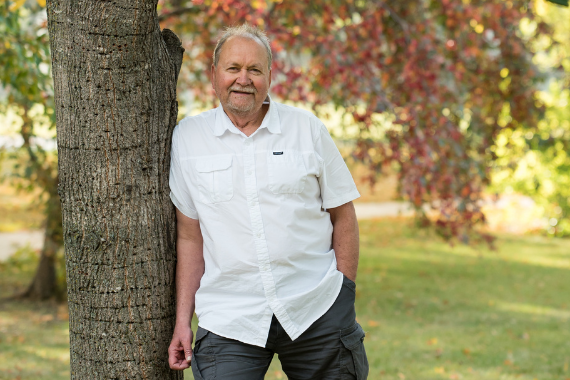 Lawrence standing against a tree